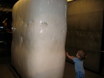 Nora and a large block of ice at a science museum.