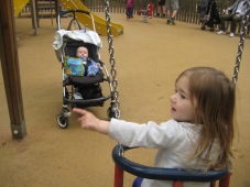 Nora showing Max how to use the swings.